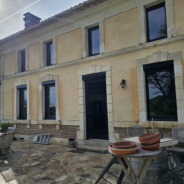 Maison rénovée par Menuiseries Ménesplesiennes avec des portes et fenêtres en PVC de couleur noire à Montpon-Ménestérol